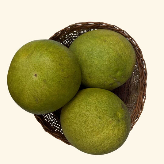 The Staple Kaka green pomelos in a wicker basket on a white background